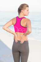 Wear view of fit woman looking at the sea with hands on back