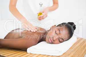 Masseuse pouring massage oil on a pretty woman back