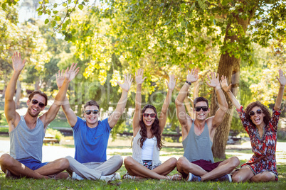 Happy friends raising their hands in the park