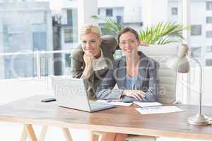 Smiling businesswomen looking at camera and working together