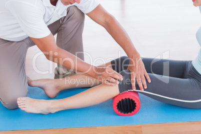 Trainer working with woman on exercise mat