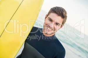 Man in wetsuit with a surfboard on a sunny day