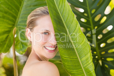 Beautiful blonde smiling at camera behind leaf