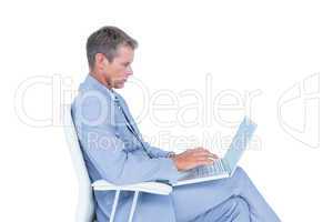 Handsome businessman sitting on a swivel chair and using his lap