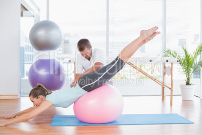 Trainer working with woman on exercise ball