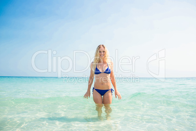 Smiling blonde woman walking into the ocean