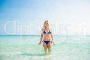 Smiling blonde woman walking into the ocean