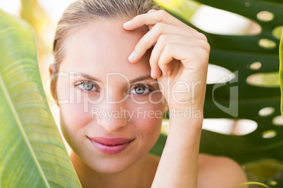 Beautiful blonde smiling at camera behind leaf