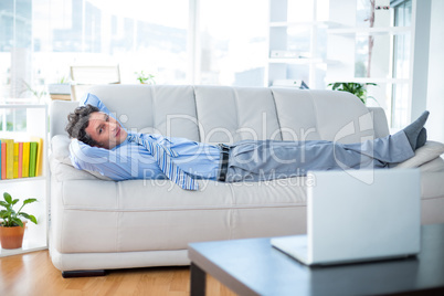 Businessman looking at camera and lying on couch