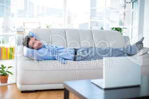 Businessman looking at camera and lying on couch