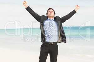 Happy businessman cheering at the beach