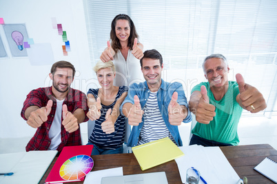 Creative business team gesturing thumbs up in meeting