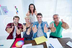 Creative business team gesturing thumbs up in meeting