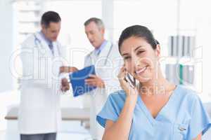 Nurse phoning while her colleagues working