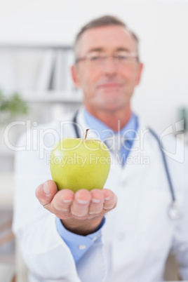 Smiling doctor showing apple