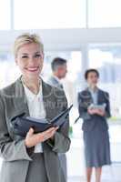 Smiling businesswoman holding files and looking at camera