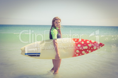 Pretty blonde woman holding surf board