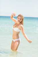 Happy pretty blonde looking at camera into the sea