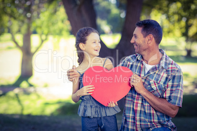 Father and daughter holding a heart in the park