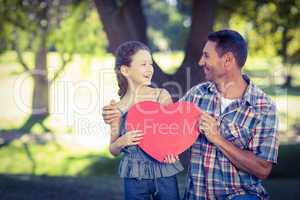 Father and daughter holding a heart in the park