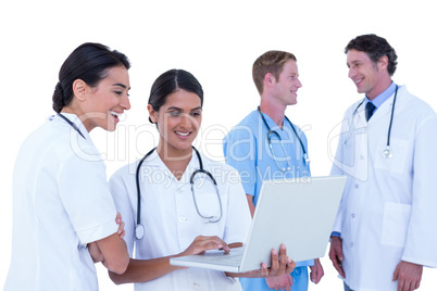 Doctors and nurses discussing and using laptop