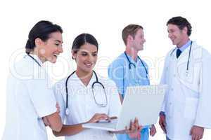 Doctors and nurses discussing and using laptop
