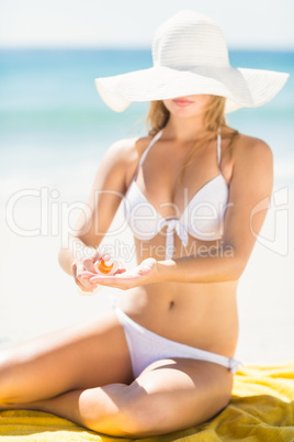 Pretty blonde woman putting sun tan lotion on her hand