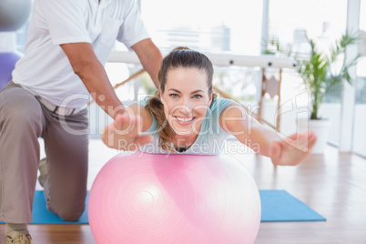 Trainer working with woman on exercise ball