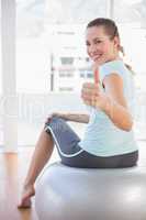 Woman looking at camera and sitting on exercise ball