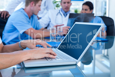 Doctor typing on keyboard with her team behind