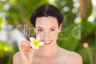 Happy brunette holding a white flower