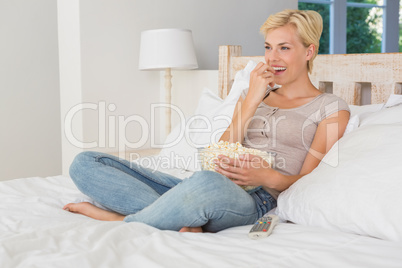 Smiling blonde woman eating pop corn
