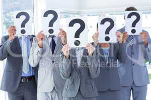 Business colleagues hiding their face with question mark sign