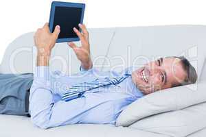 Relaxing businessman on a sofa with a tablet