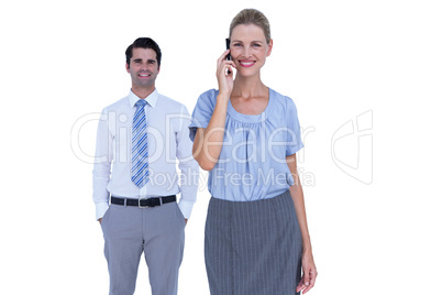 Businesswoman having phone call while her colleague posing