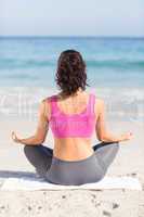 Wear view of fit woman doing yoga beside the sea