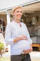 Smiling blonde pregnant hands on his belly