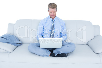 Handsome businessman sitting on sofa using his laptop Handsome businessman sitting on sofa using his laptop