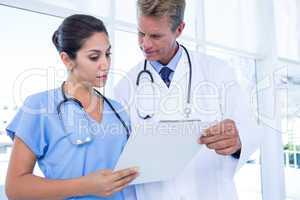 Serious doctors looking at clipboard