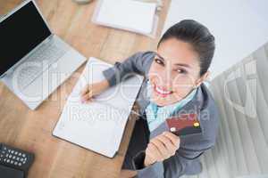 Smiling businesswoman looking at camera with credit card