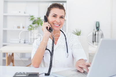 Doctor doing phone call while she using computer