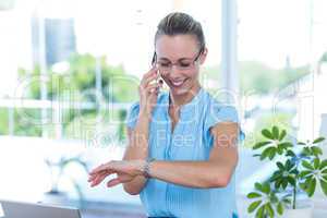 Smiling businesswoman having a phone call and checking time