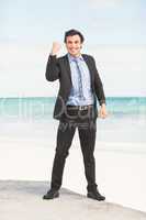 Happy businessman cheering at the beach