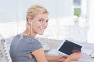 Smiling businesswoman holding credit card and tablet