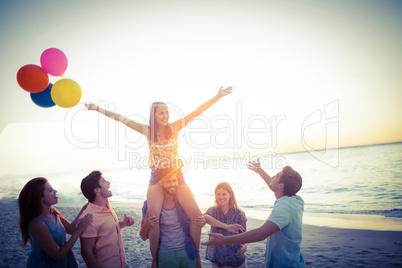 Happy friends dancing on the sand with balloon