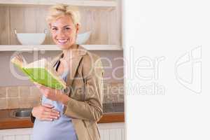 Blonde pregnancy smiling at camera and take a book