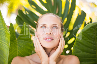 Beautiful blonde smiling at camera behind leaf