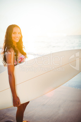 Pretty brunette with a surfboard on a sunny day