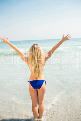 Pretty blonde woman with arms outstretched at the beach