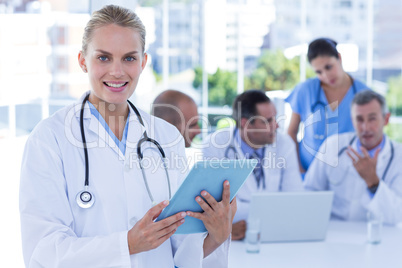 Smiling female doctor looking at clipboard while her colleagues